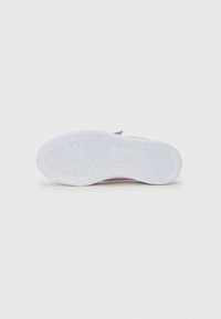 Semelle de sneaker blanche avec une surface en caoutchouc texturée, présentant une accent rose et un patch gris près du talon. Forme plate et légèrement courbée.