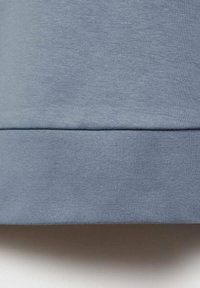 Light blue cotton fabric featuring a smooth texture. The hem is slightly folded, displaying consistent stitching and a clean finish.
