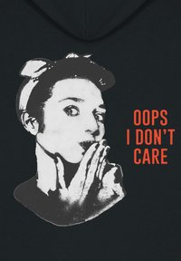 Sudadera con capucha negra que presenta un gráfico blanco de una persona con la mano en la boca y el texto "OOPS I DON'T CARE" en naranja.