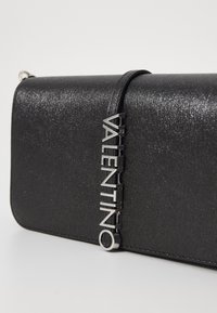 Black clutch bag with textured fabric, featuring a silver "Valentino" logo accent. It has a sleek, rectangular shape and a thin strap.