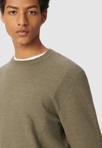 Olivgrüner Pullover mit geripptem Textur an den Ärmeln und glattem Körper. Verfügt über einen runden Halsausschnitt und leichte Nähdetails.