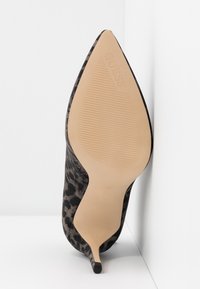 Zapato de tacón alto con estampado de leopardo negro y marrón, punta puntiaguda y tacón de aguja delgado. Material superior liso y suela texturizada.