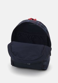 Zaino con una superficie esterna blu navy, motivo a quadri in blu scuro e rosso, apertura con zip e ampio scomparto interno.