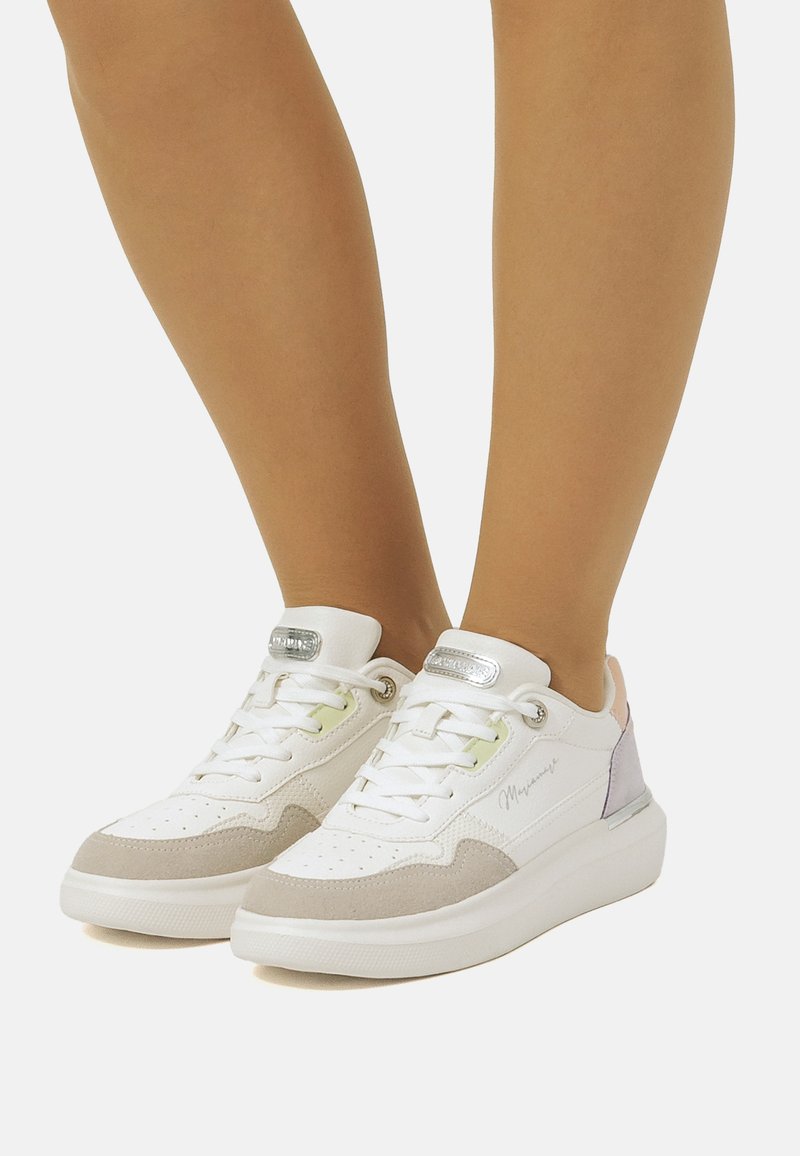 Baskets blanches avec une tige texturée, des accents en daim gris clair et des détails en pastel violet et rose. Équipées de lacets blancs et d'un logo.
