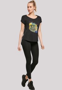 Svart t-skjorte med grafisk trykk av Dumbo, sammen med svarte leggings. T-skjorten har en avslappet passform og korte ermer.