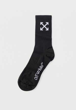 Schwarze Sportsocke mit weißem Off-White-Logo auf dem Fuß und einem Emblem mit gekreuzten Pfeilen nahe dem oberen Bündchen.