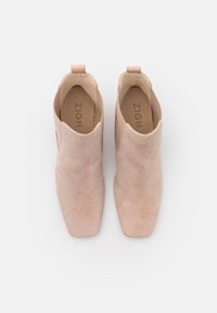 Botines de ante rosa con diseño de punta afilada, paneles laterales elásticos y una lengüeta en el talón para poner y quitar fácilmente.