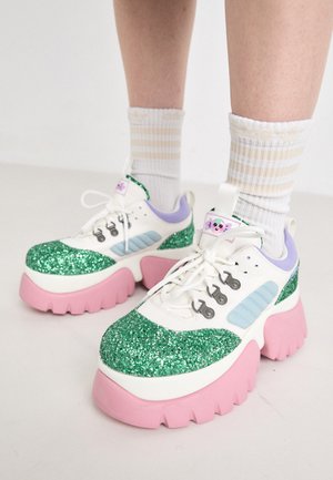 Platvormi spordijalatsid, millel on valge ja pastelsed värvid, roheline glittersüvend, roosa tall ja mitmed silmad. Omab mängulisi aktsente.