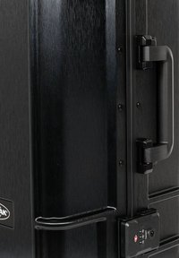 Valigia rigida nera con superficie texture, manico integrato regolabile e serratura a combinazione laterale per la sicurezza.