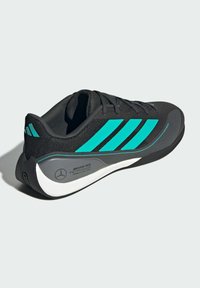 Black athletic shoe with turquoise three-stripe design, mesh upper, padded collar, and white sole featuring branding on the heel.