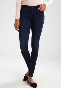 Mörkblå tajta jeans med en slät yta, med medelhög midja, lätt blekning och en klassisk femfickdesign.