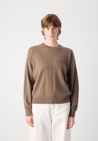 Κα�φέ πουλόβερ με στρογγυλή λαιμόκοψη, μακριά μανίκια και ελαφρώς χαλαρή εφαρμογή. Μαλακή υφή και λεπτομέρειες στο στρίφωμα και στους καρπούς.