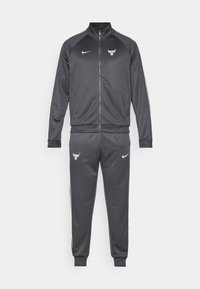 Mørkegrå Nike Chicago Bulls træningsdragt med lynlåsjakke og matchende joggerbukser, der har hold- og mærkelogoer.