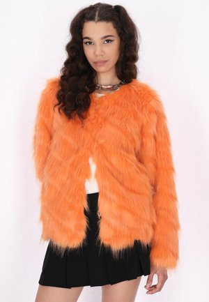 Oranje faux fur jas met lange mouwen, voorzien van een ronde halslijn en een zachte, gestructureerde oppervlakte. Gecombineerd met een zwarte geplooide rok.