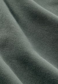 Tecido de algodão cinza com uma textura suave e macia, apresentando finas nervuras verticais e um leve caimento. A luz reflete suavemente na superfície.