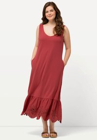 Rotes ärmelloses Kleid mit tiefem V-Ausschnitt, seitlichen Taschen und gewelltem Saum mit floralem Stickmuster. Weicher, leichter Stoff.