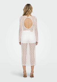 Weißes Spitzekleid mit langen Ärmeln, offenem Rücken, Midi-Länge und geometrischem Muster. Besitzt einen weichen, strukturierten Stoff und eine schmale Passform.