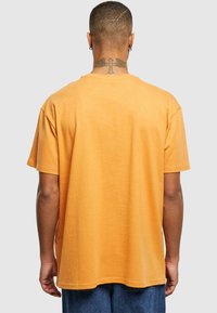 Kortærmet t-shirt i sennepsgul, lavet af blødt stof. Har en afslappet pasform og en rundt halsudskæring, med minimale syninger.