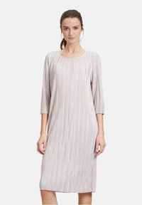 Helles graues Kleid mit Rundhalsausschnitt und dreiviertel Ärmeln, das eine vertikale Rippstruktur und eine gerade Silhouette aufweist.