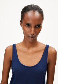 Marineblauwe tanktop met brede schouderbanden, ronde halslijn, gemaakt van een gladde, lichte stof, met een aansluitende silhoeët.