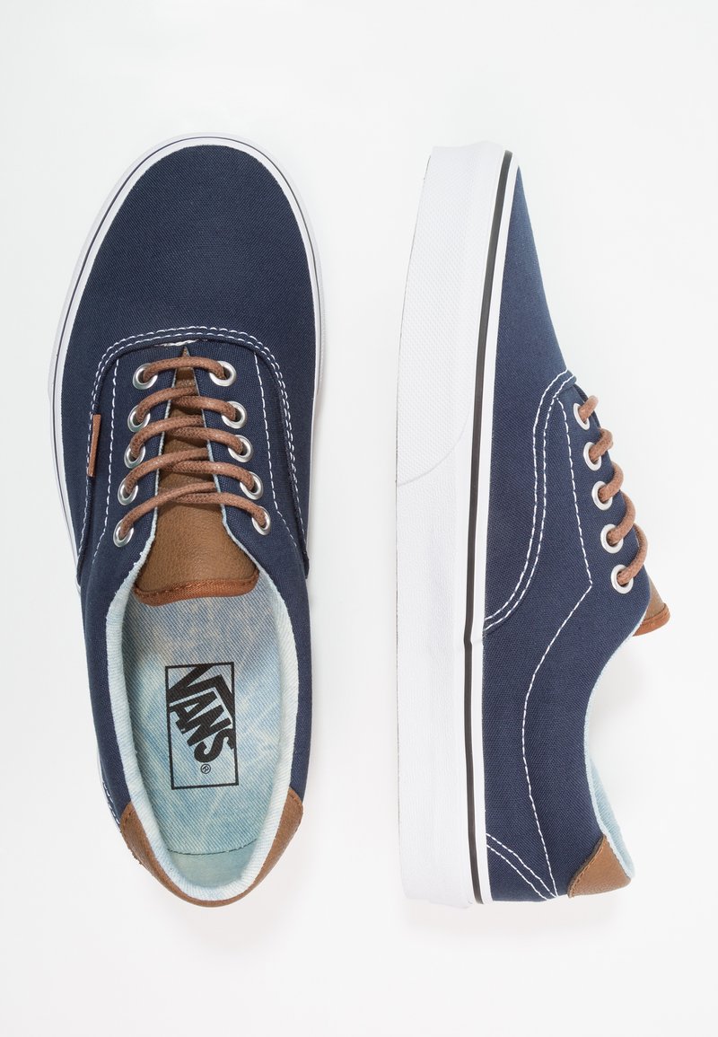 Zapatillas Vans de color azul marino con suelas blancas, cordones marrones y detalles en marrón, mostradas desde vistas superior y lateral sobre un fondo blanco.