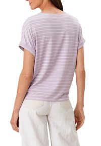 Camiseta de rayas moradas claras con mangas enrolladas, de tejido suave, corte relajado y escote redondo, combinada con pantalones de pierna ancha de color claro.
