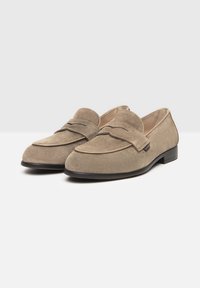 Beige Wildleder-Lederleisten mit runder Zehenpartie, gestickten Details und einem dekorativen Penny-Loafer-Riemen. Verfügt über einen niedrigen, flachen schwarzen Absatz.