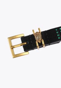 Czarny zamszowy pasek z prostokątną złotą metalową klamrą oraz dekoracyjnym złotym detalem w kształcie muszli, ozdobionym zielonymi kamieniami szlachetnymi.