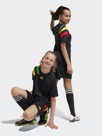 Schwarze Fußballtrikots mit bunten gestreiften Akzenten in Grün, Gelb und Rot. Die Kleidung umfasst schwarze Shorts und knielange gestreifte Socken.