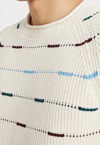 Maglione lavorato a maglia in crema con righe orizzontali in verde scuro, blu e bordeaux. Presenta un collo a coste e un tessuto lavorato.