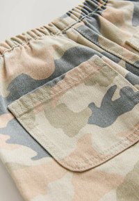 Shorts camouflage présentant une palette de couleurs beige, gris et vert avec une taille élastique froncée et une poche arrière avec des coutures ton sur ton.