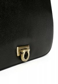 Borsa a mano in pelle nera con superficie testurizzata, hardware color oro con chiusura circolare e nome del marchio impresso.