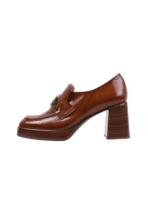 Mocasín de charol marrón de tacón alto con punta cuadrada, hebilla decorativa y un tacón grueso y texturizado que parece madera.