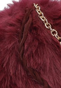 Burgundy faux fur material features a braided dark brown suede accent and a gold-tone chain for an added detail and rich texture.
