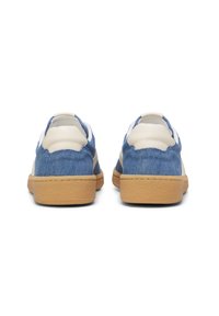 Zapatillas de denim con parte superior de tejido azul, detalles en cuero beige y suela de goma. Presentan un patrón texturizado y un cuello acolchado.