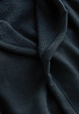 Donkere fleece jas met ribbeltextuur, voorzien van een zachte, pluchen binnenvoering en een gladde afwerking langs de randen.