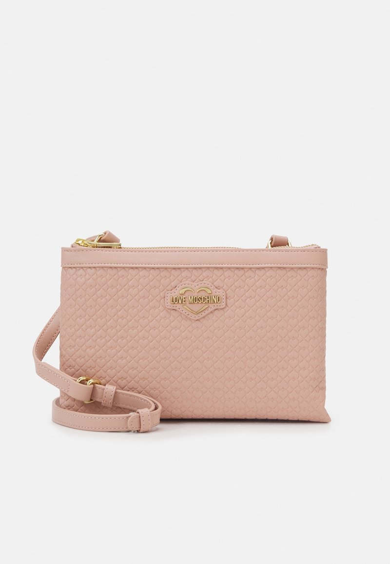 Small pink quilted handbag with a gold logo and adjustable strap, featuring a zippered closure and heart-patterned texture.