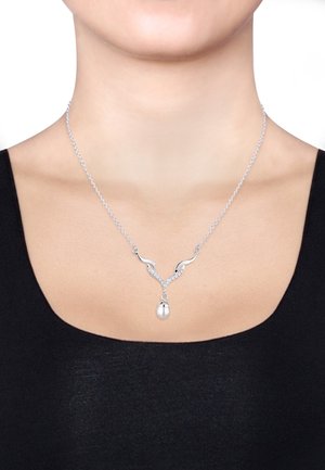 Silberne Halskette mit einem aufwändigen Design, das sich durch gedrehte Akzente und einen zentralen Anhänger in Eiform auszeichnet, der auf einem schwarzen Oberteil zur Geltung kommt.