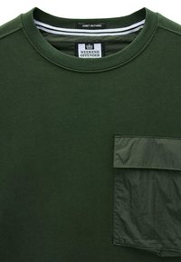 Camisa de cuello redondo de color verde oscuro con un bolsillo en el pecho de tela brillante y dos etiquetas dentro del cuello que dicen "WEEKEND OFFENDER" y "ADMIT NOTHING."