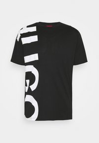 Sort kortærmet T-shirt med stort hvidt vertikalt grafisk tekst på venstre side, strækkende sig fra skulderen til sømmen.