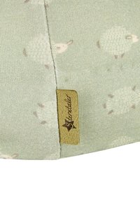 Green cotton fabric featuring a sheep pattern, soft texture, with a brown leather tag embossed with "Sterntaler" on the edge.