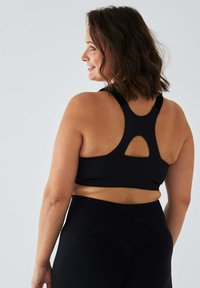 Czarny sportowy biustonosz z wycięciem na plecach w stylu racerback. Wykonany z prążkowanej tkaniny, o gładkiej fakturze i minimalistycznym stylu.