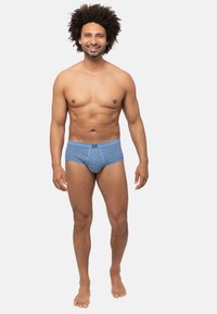 Slip blu con motivo, dotati di elastico in vita, taglio a media altezza e vestibilità aderente, indossati da un modello maschile su uno sfondo neutro.