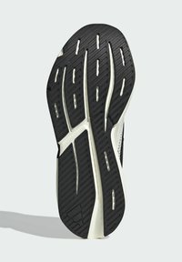 Svart gummisula med ett texturerat mönster och spår, med vita detaljer. Formad kontur med en lätt böj vid hälen.