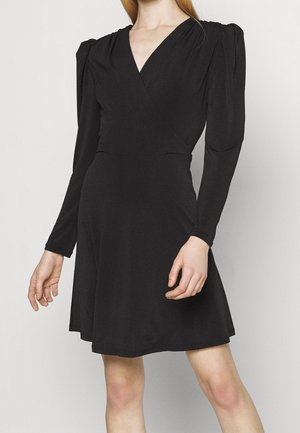 Robe noire à manches longues ajustées, décolleté en V et épaules froncées. Fabriquée en tissu lisse avec un ourlet évasé.