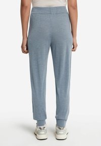 Ljusblåa joggers med en avslappnad passform, muddade anklar och en mjuk textur. Materialet verkar mjukt, lämpligt för avslappnad användning eller träning.