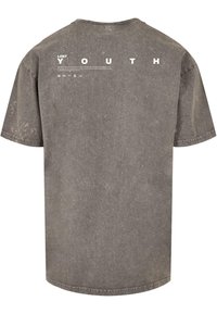 Grå oversized t-shirt med en sliten textur. Har vit text "LOST YOUTH" tryckt på baksidan, med rund halsringning och korta ärmar.
