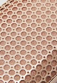 Teksturowana powierzchnia w kolorze różowego złota z sześciokątnymi i ośmiokątnymi wzorami o brokatowym wykończeniu, zapewniająca nowoczesny i elegancki wygląd.