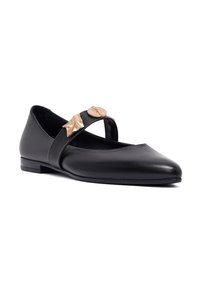 Scarpa flat nera in pelle con punta a forma affilata, caratterizzata da una fascia incrociata decorata con due dettagli in bronzo. Texture liscia e tacco basso.