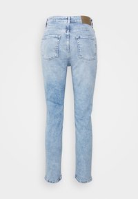 Jeans de ganga azul claro com um corte reto, cintura média e dois bolsos posteriores. Apresenta um patch de couro bege na cintura.